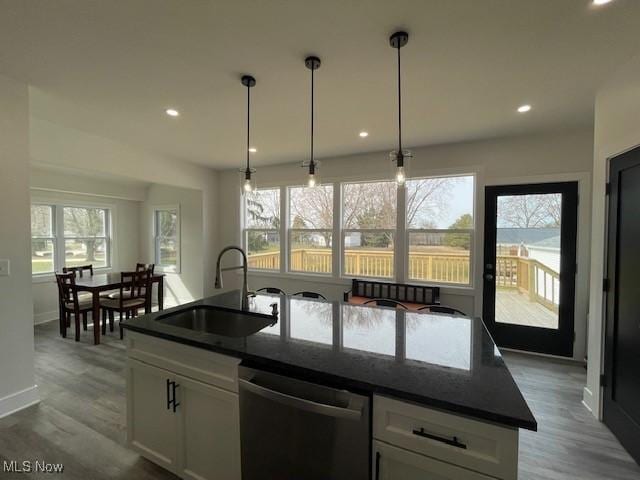 kitchen featuring dishwasher, sink, an island with sink, a healthy amount of sunlight, and white cabinetry