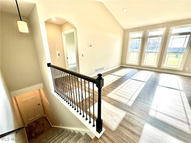 staircase with wood-type flooring and high vaulted ceiling