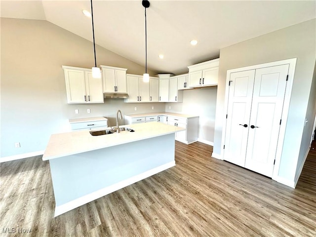 kitchen featuring white cabinetry, sink, an island with sink, and vaulted ceiling