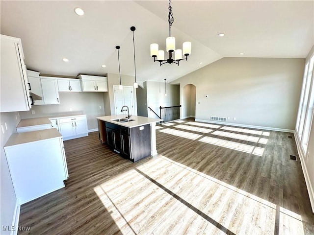 kitchen with sink, an island with sink, decorative light fixtures, vaulted ceiling, and white cabinets