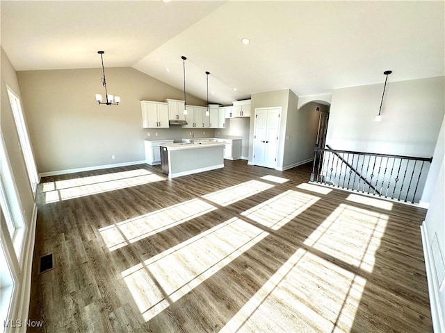 unfurnished living room with lofted ceiling, an inviting chandelier, dark wood-type flooring, and sink