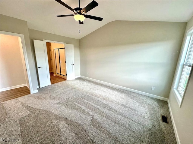 unfurnished bedroom with carpet flooring, ceiling fan, and vaulted ceiling