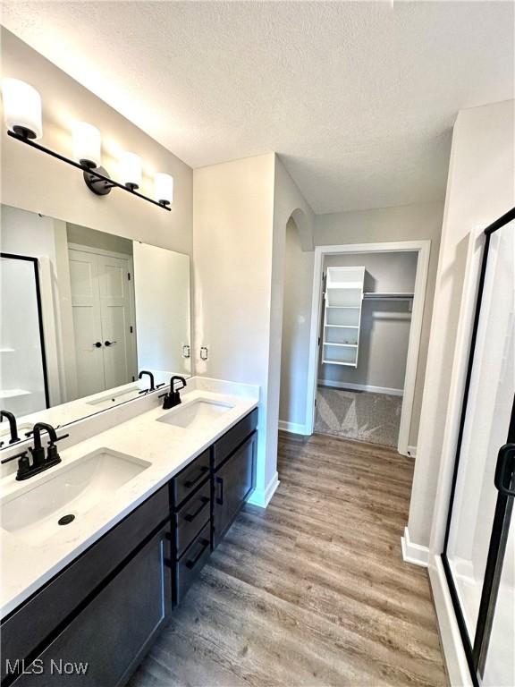 bathroom with vanity, hardwood / wood-style floors, a textured ceiling, and a shower