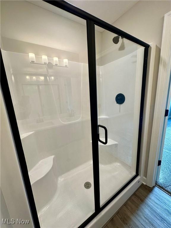 bathroom with hardwood / wood-style flooring and an enclosed shower