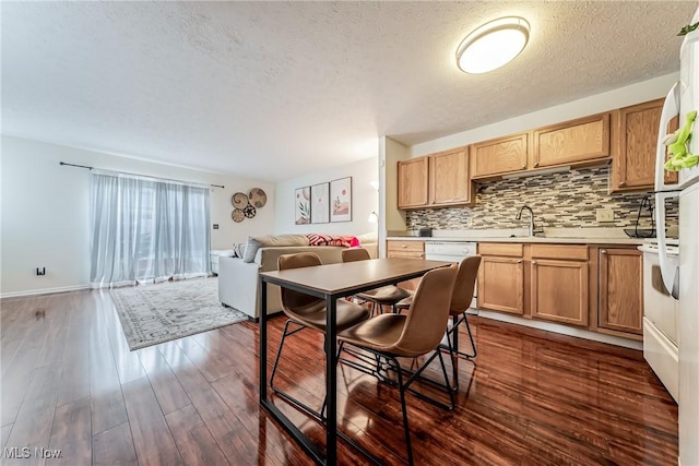 kitchen with white dishwasher, sink, a textured ceiling, tasteful backsplash, and dark hardwood / wood-style flooring