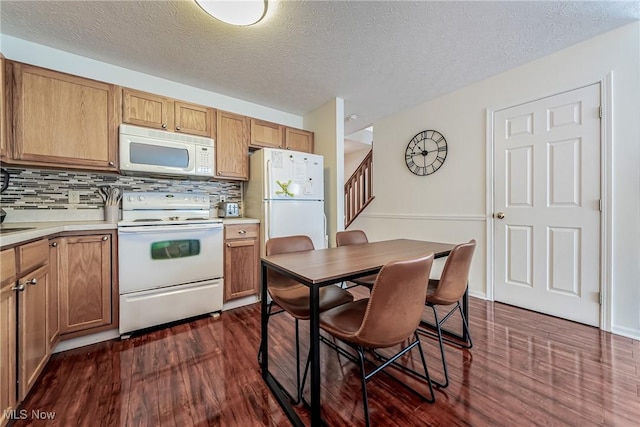 kitchen featuring a textured ceiling, white appliances, dark wood-type flooring, and tasteful backsplash