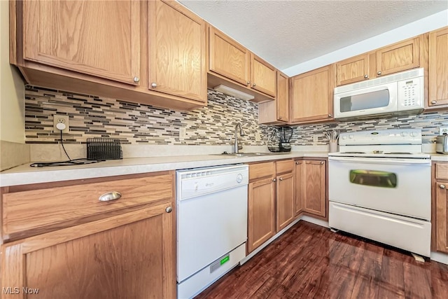 kitchen with backsplash, dark hardwood / wood-style flooring, white appliances, and sink