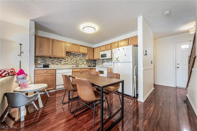 kitchen with sink, dark hardwood / wood-style floors, backsplash, a textured ceiling, and white appliances