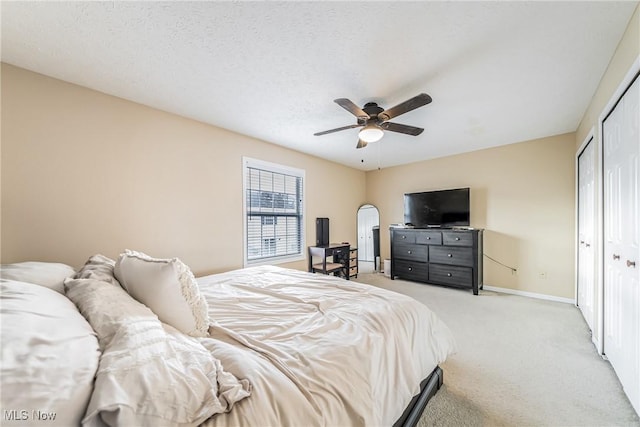 bedroom with a textured ceiling, a closet, light colored carpet, and ceiling fan