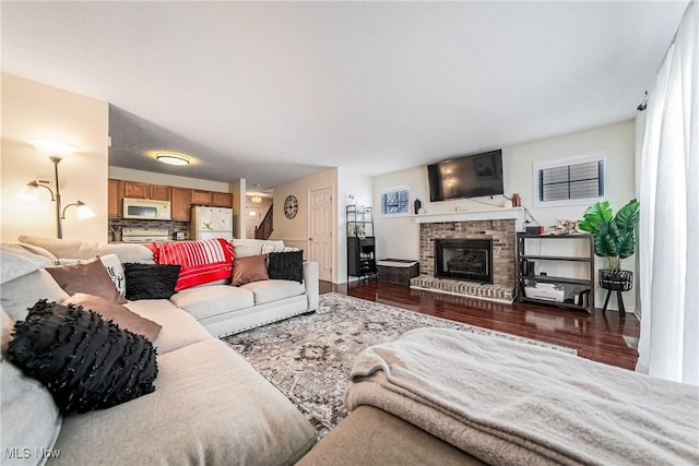 living room featuring dark hardwood / wood-style flooring and a brick fireplace