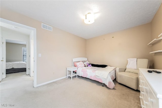 bedroom featuring light carpet and a textured ceiling