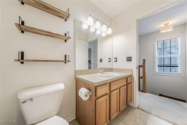 bathroom with tile patterned flooring, vanity, a textured ceiling, and toilet