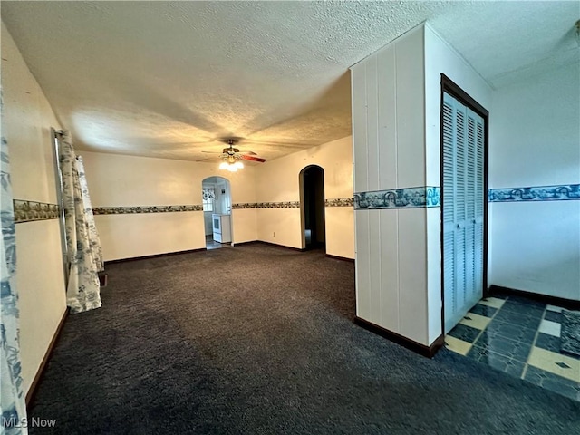 carpeted spare room featuring a textured ceiling and ceiling fan