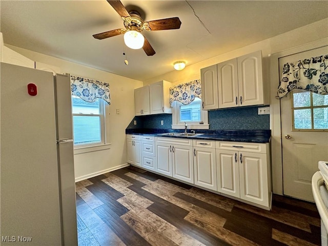 kitchen featuring ceiling fan, dark hardwood / wood-style flooring, white refrigerator, decorative backsplash, and white cabinets