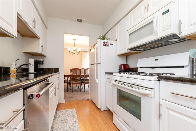 kitchen featuring white cabinetry, light hardwood / wood-style flooring, a notable chandelier, dark stone countertops, and white appliances