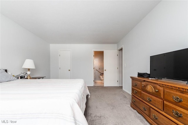 bedroom with ensuite bathroom and light colored carpet