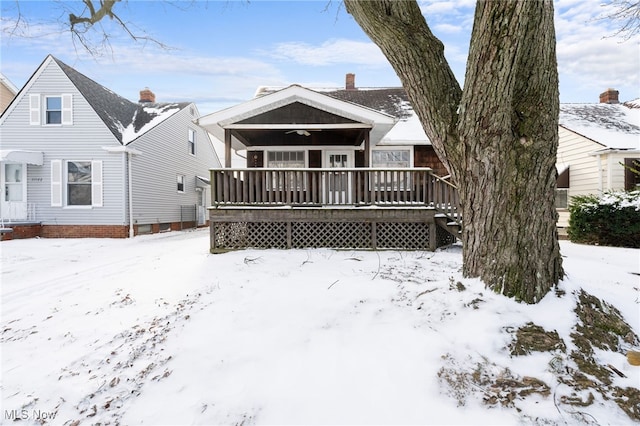 snow covered rear of property with a deck