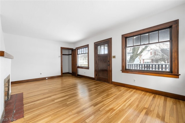 unfurnished living room featuring light hardwood / wood-style flooring and a brick fireplace