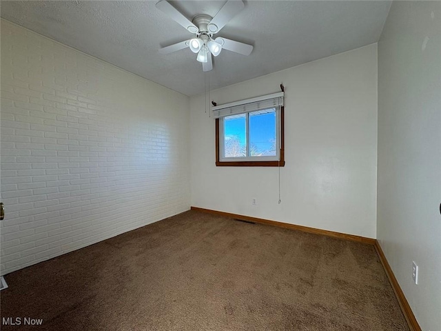 carpeted spare room featuring ceiling fan and brick wall