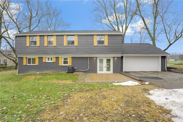 rear view of property with a garage, central air condition unit, a yard, and french doors