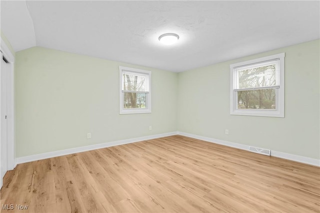 spare room featuring lofted ceiling and light hardwood / wood-style floors