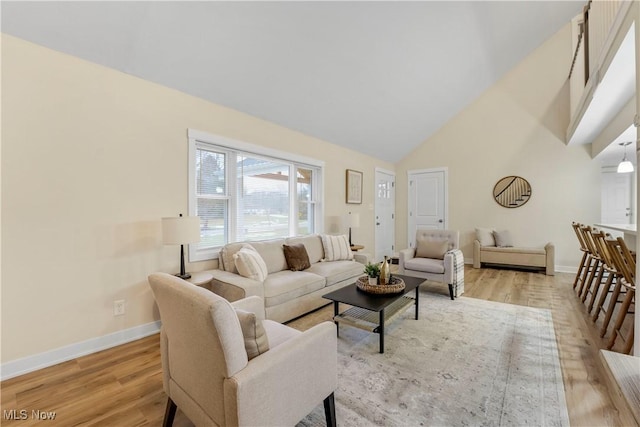 living room with high vaulted ceiling and light hardwood / wood-style flooring