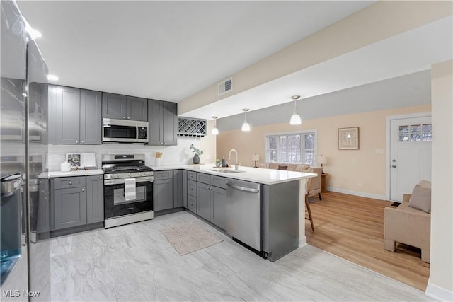 kitchen with gray cabinetry, hanging light fixtures, kitchen peninsula, and appliances with stainless steel finishes