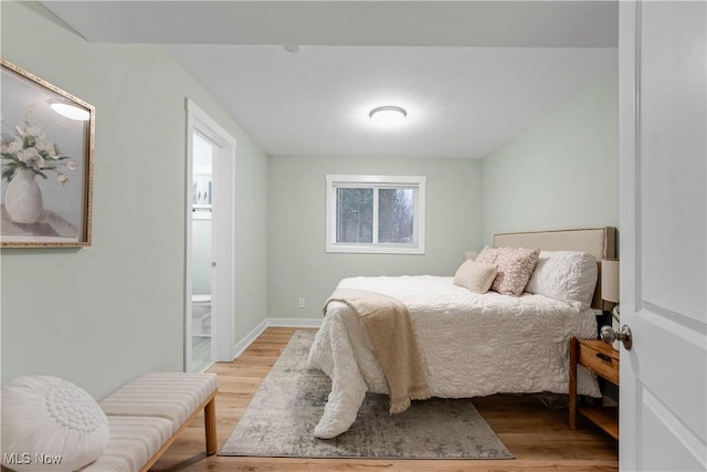 bedroom with connected bathroom and light wood-type flooring