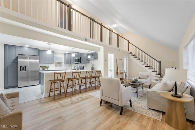 living room with a towering ceiling, a healthy amount of sunlight, and light hardwood / wood-style floors