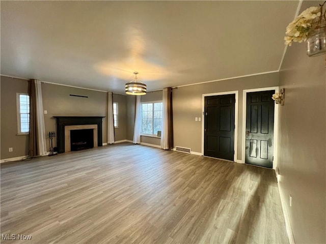 unfurnished living room featuring a chandelier and hardwood / wood-style floors