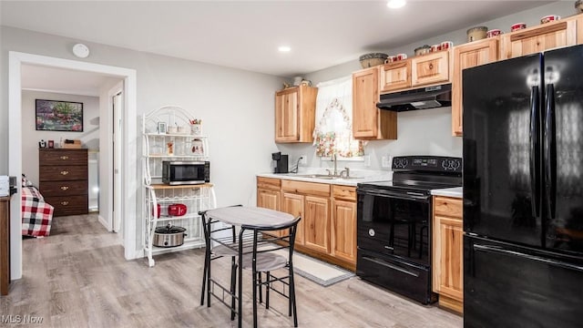 kitchen with light brown cabinetry, light hardwood / wood-style floors, sink, and black appliances