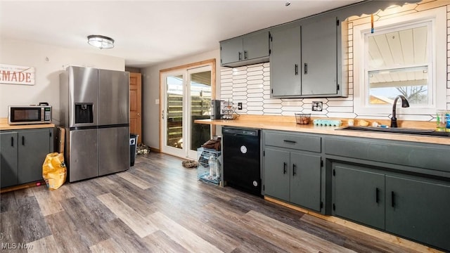 kitchen with appliances with stainless steel finishes, tasteful backsplash, sink, gray cabinetry, and dark hardwood / wood-style flooring