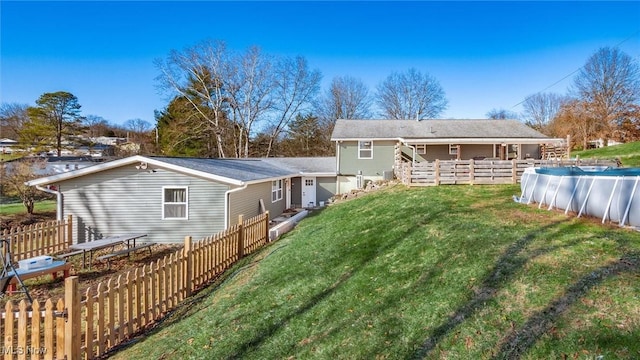 rear view of property featuring a covered pool and a yard