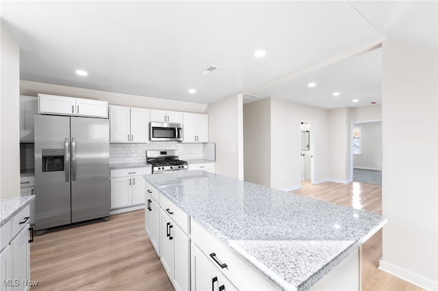 kitchen featuring a center island, white cabinets, stainless steel appliances, and light hardwood / wood-style floors