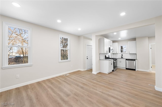 kitchen featuring appliances with stainless steel finishes, tasteful backsplash, sink, light hardwood / wood-style flooring, and white cabinets