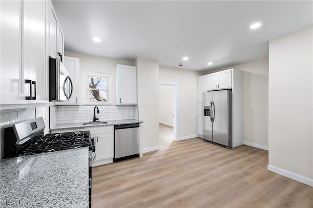 kitchen featuring light stone countertops, white cabinets, stainless steel appliances, and light hardwood / wood-style floors