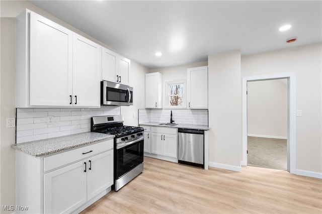 kitchen featuring white cabinets, light hardwood / wood-style floors, appliances with stainless steel finishes, and tasteful backsplash