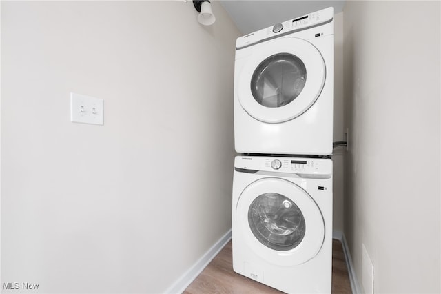 laundry area with wood-type flooring and stacked washing maching and dryer