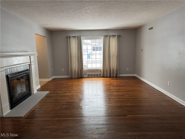 unfurnished living room featuring a textured ceiling, dark hardwood / wood-style floors, and a brick fireplace