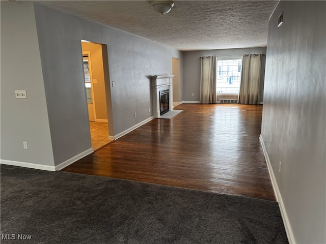 unfurnished living room featuring dark hardwood / wood-style floors and a textured ceiling