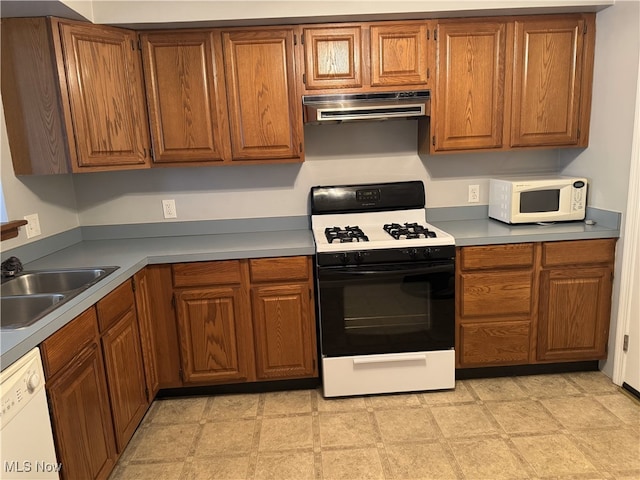 kitchen with white appliances, sink, and range hood