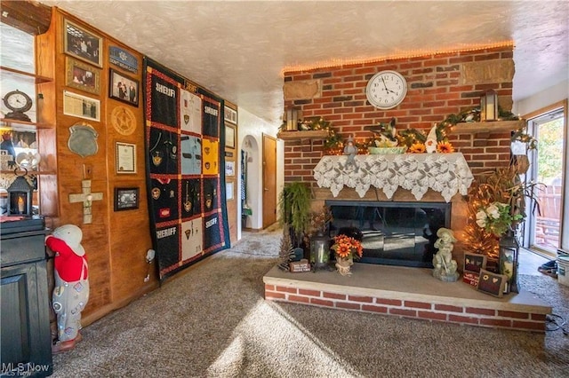 living room featuring carpet flooring, a textured ceiling, and a brick fireplace