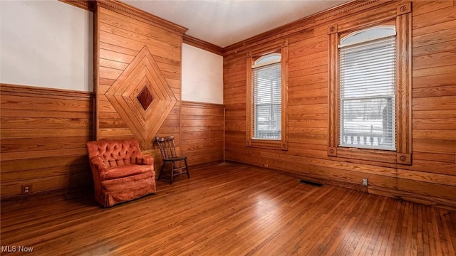 unfurnished room featuring hardwood / wood-style flooring, crown molding, and wooden walls