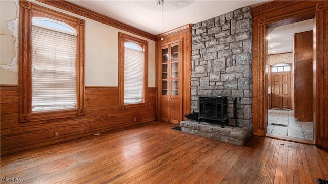 unfurnished living room with hardwood / wood-style floors, a healthy amount of sunlight, and a wood stove