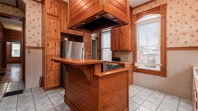 kitchen with premium range hood, light tile patterned floors, tile walls, and stainless steel gas stovetop