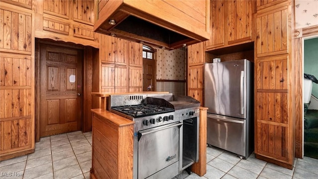 kitchen featuring wooden walls, light tile patterned floors, custom range hood, and appliances with stainless steel finishes