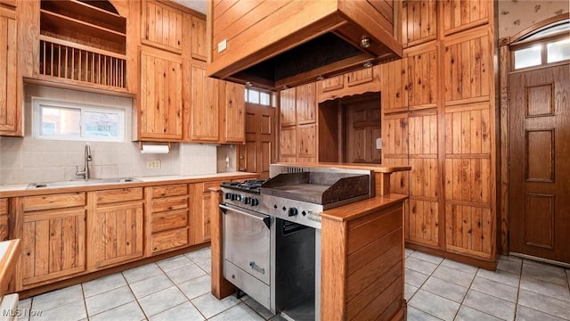 kitchen featuring decorative backsplash, light tile patterned floors, sink, and stainless steel stove