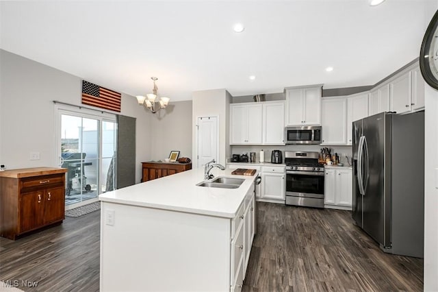 kitchen featuring appliances with stainless steel finishes, sink, white cabinets, hanging light fixtures, and a center island with sink