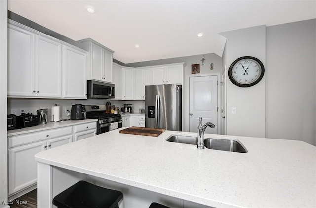 kitchen with an island with sink, appliances with stainless steel finishes, sink, and white cabinets