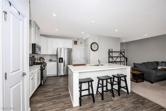 kitchen featuring a kitchen bar, sink, white cabinetry, stainless steel appliances, and a kitchen island with sink